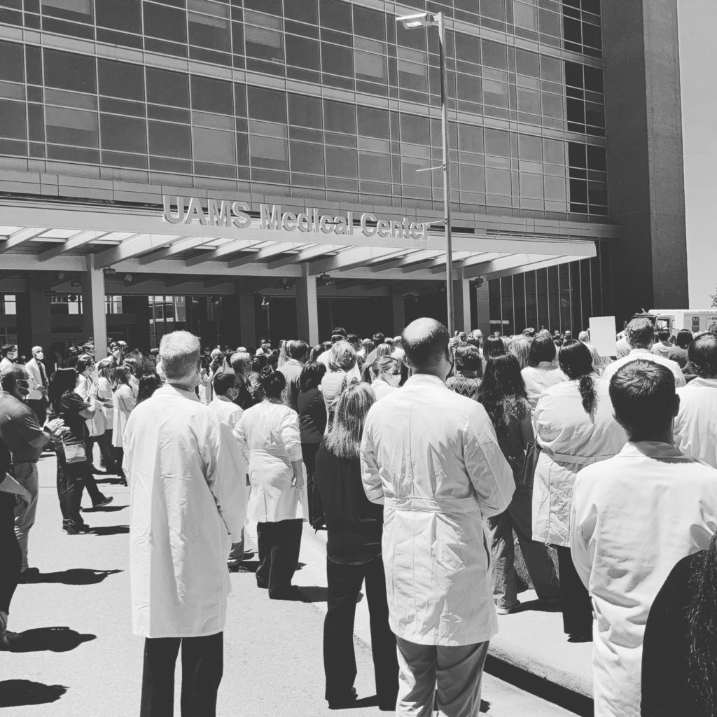 Black and white photo of medical staff standing in front of the UAMS Medical Center for the White Coats for Black Lives event