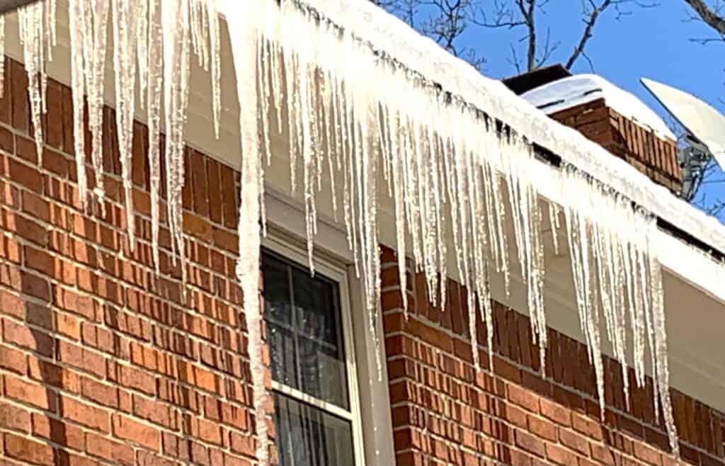 close up of icicles hanging from a roof of a house