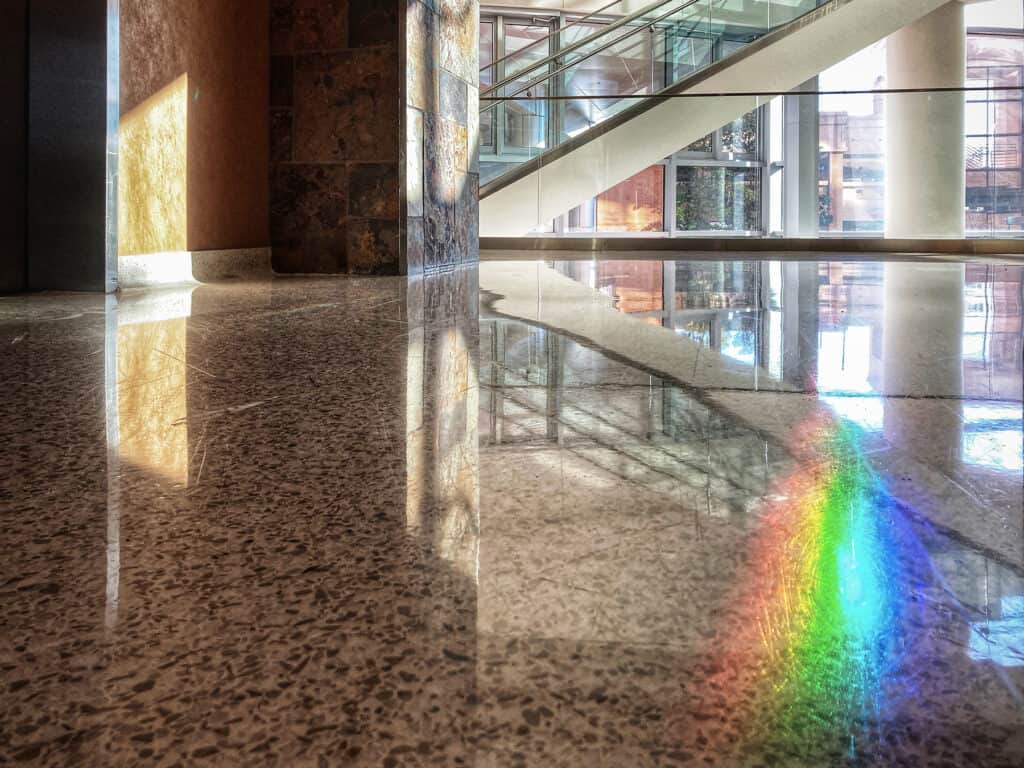 a rainbow is splayed across a floor as sunlight comes through windows in a building on the UAMS campus