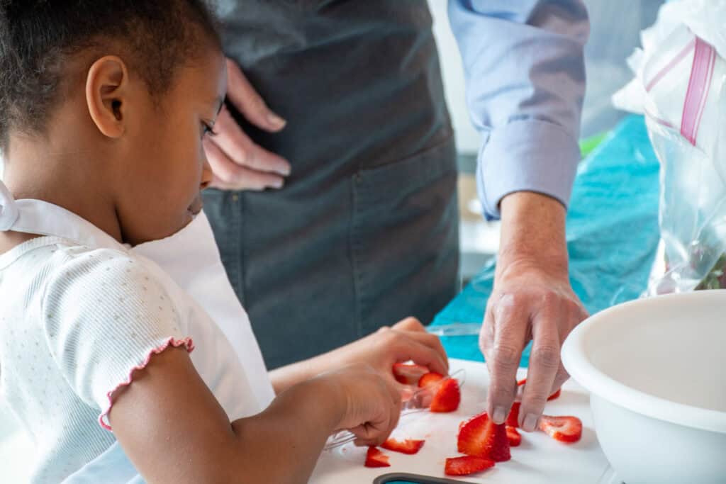 Marshallese girl cutting strawberries at a Marshallese cooking class to promote healthy nutrition.  