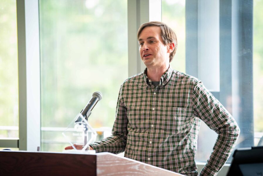 Reade Zodrow stands at a podium, reading from his fiction piece