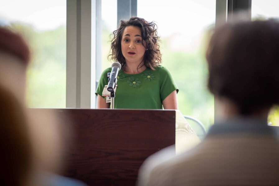 Brooke Scalzo stands at a podium at the event, reading an excerpt from her piece