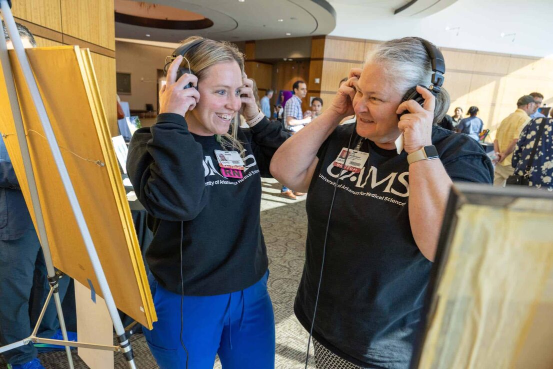 two attendees smile as they listen on headphones
