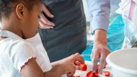 Marshallese girl cutting strawberries at a Marshallese cooking class to promote healthy nutrition.