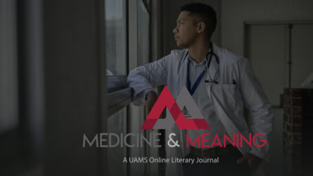 Young male doctor looking out through a window while standing alone in a hospital corridor. Logo on the picture reads Medicine and Meaning: A UAMS Online Literary Journal